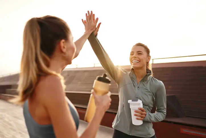 Two happy friends celebrate their rewarding workout with a highfive, showcasing their friendship and fitness passion, inspiring others to embrace a healthier, joyful, and active lifestyle